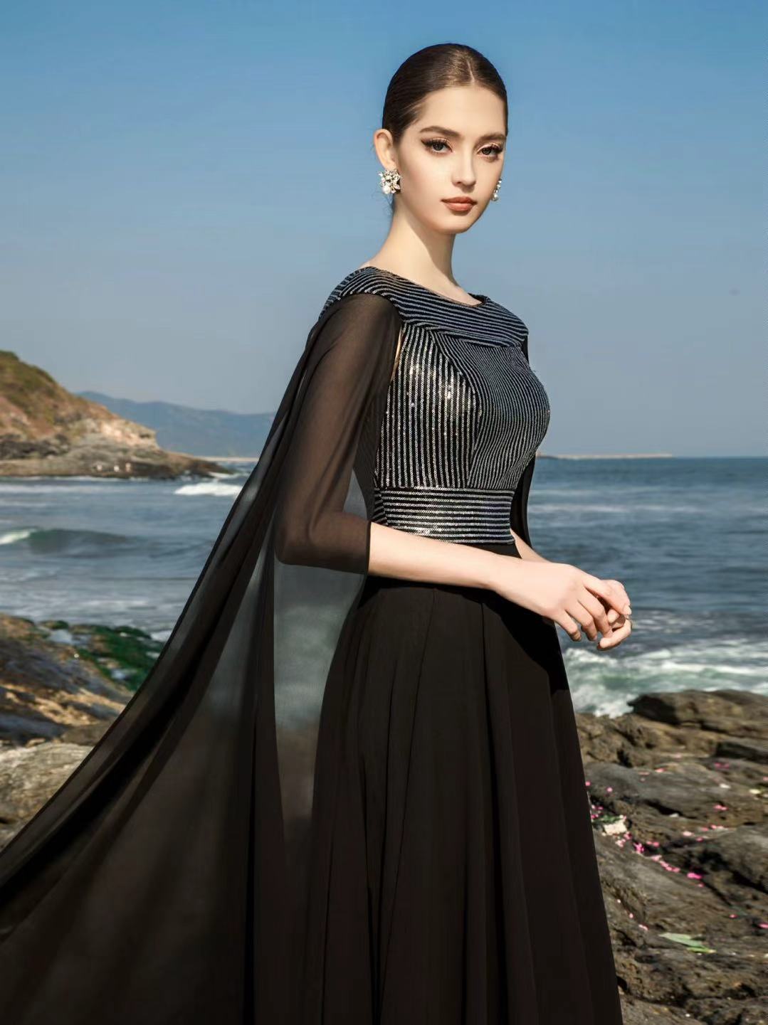 Robe de soirée noire à embellissement artisanal photographiée au bord de la mer