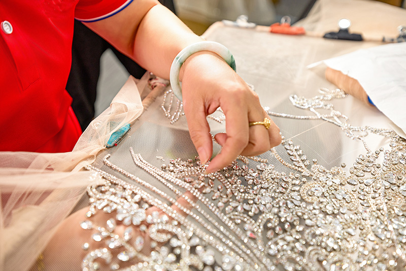 Artisan posant des paillettes à la main sur du tulle
